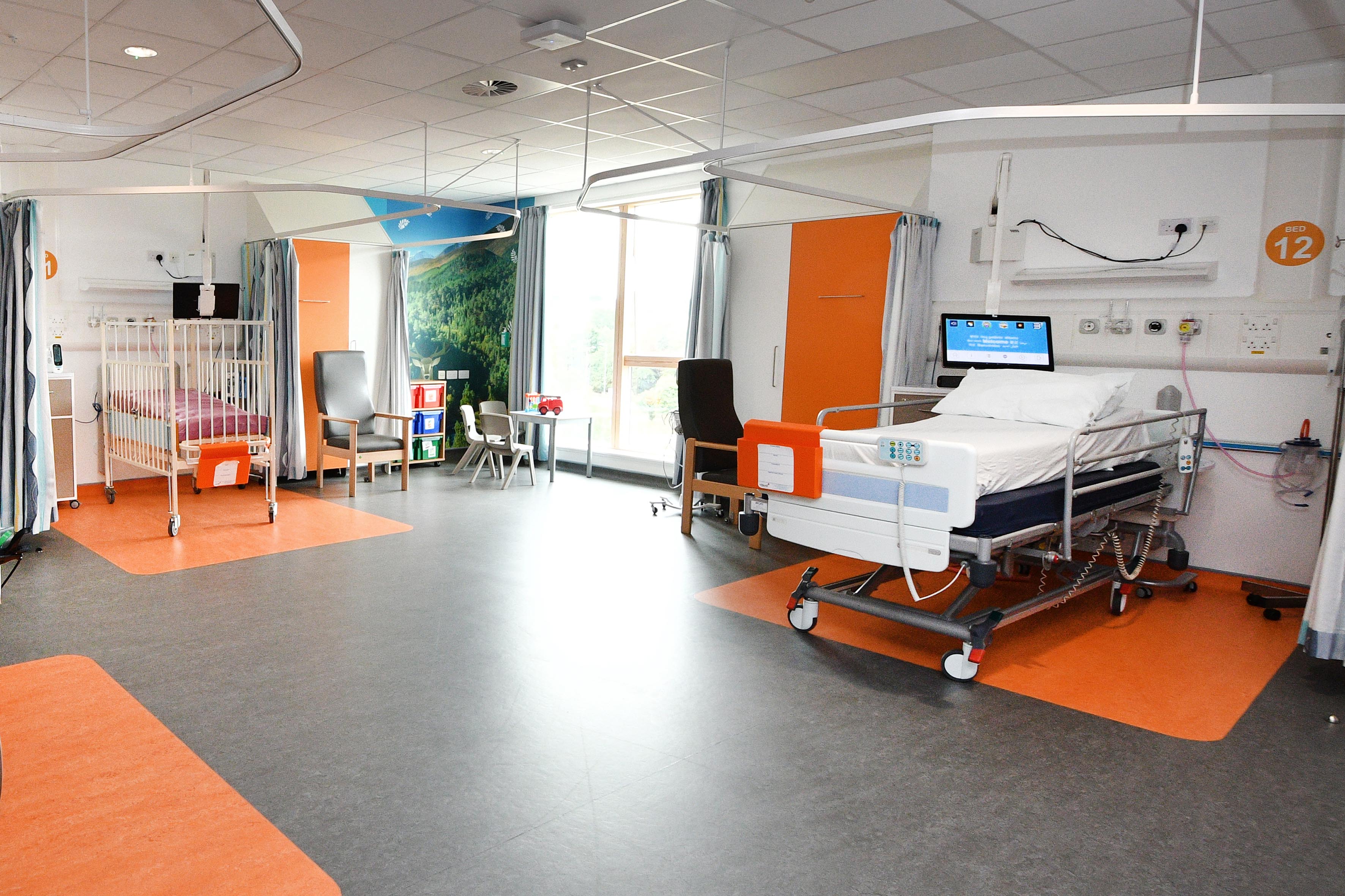 A vast room with big windows and two beds: one normal size bed and one for small children