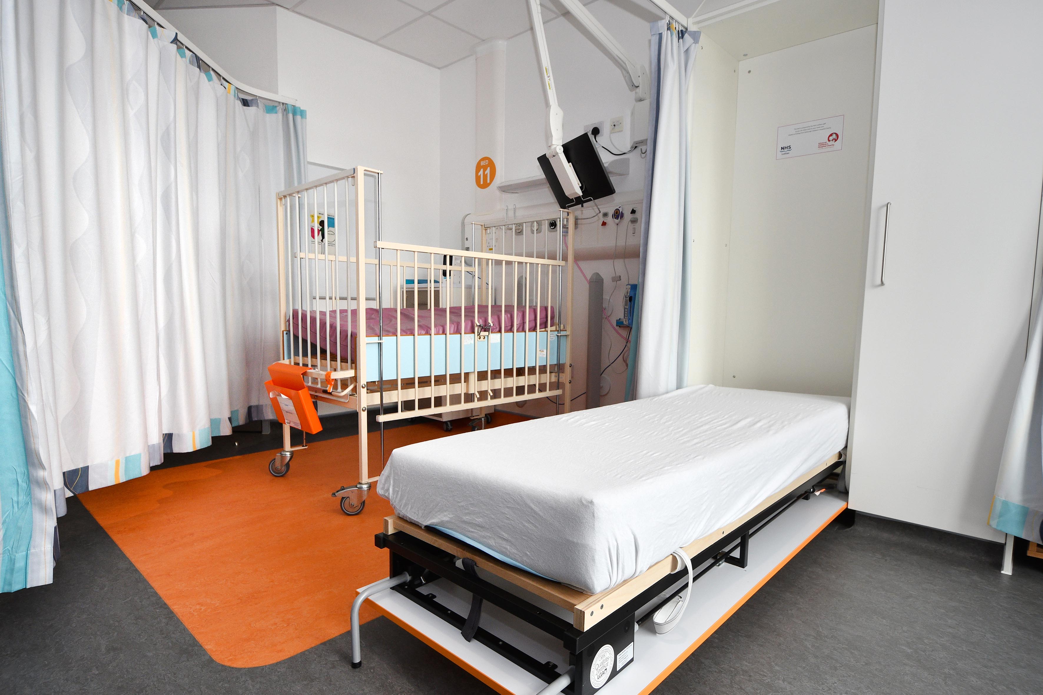 There is a room with a single parent bed for parents which is located next to a cradle for small children.