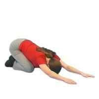 a woman Kneeling on the floor feet together and knees a little apart. Their hands are in front of them pushing downwards on the floor.