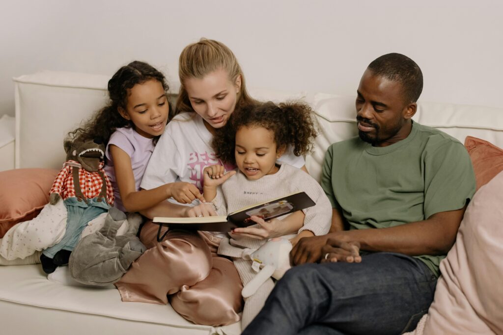 two girls reading a boox, sitting on a lounge with their parents.