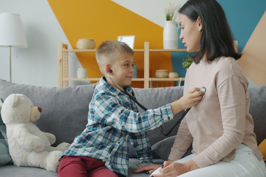 Young boy using stethoscope on mother, playing doctor at home.